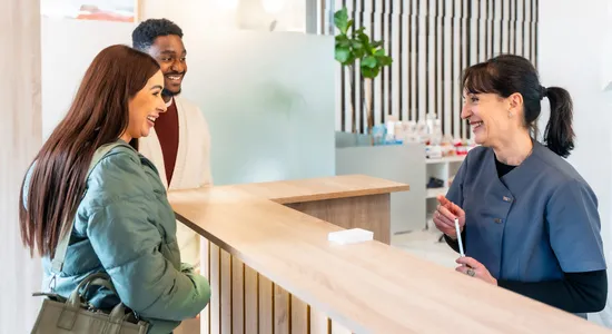 Dental receptionist checking in patients at Nov Dental front desk.